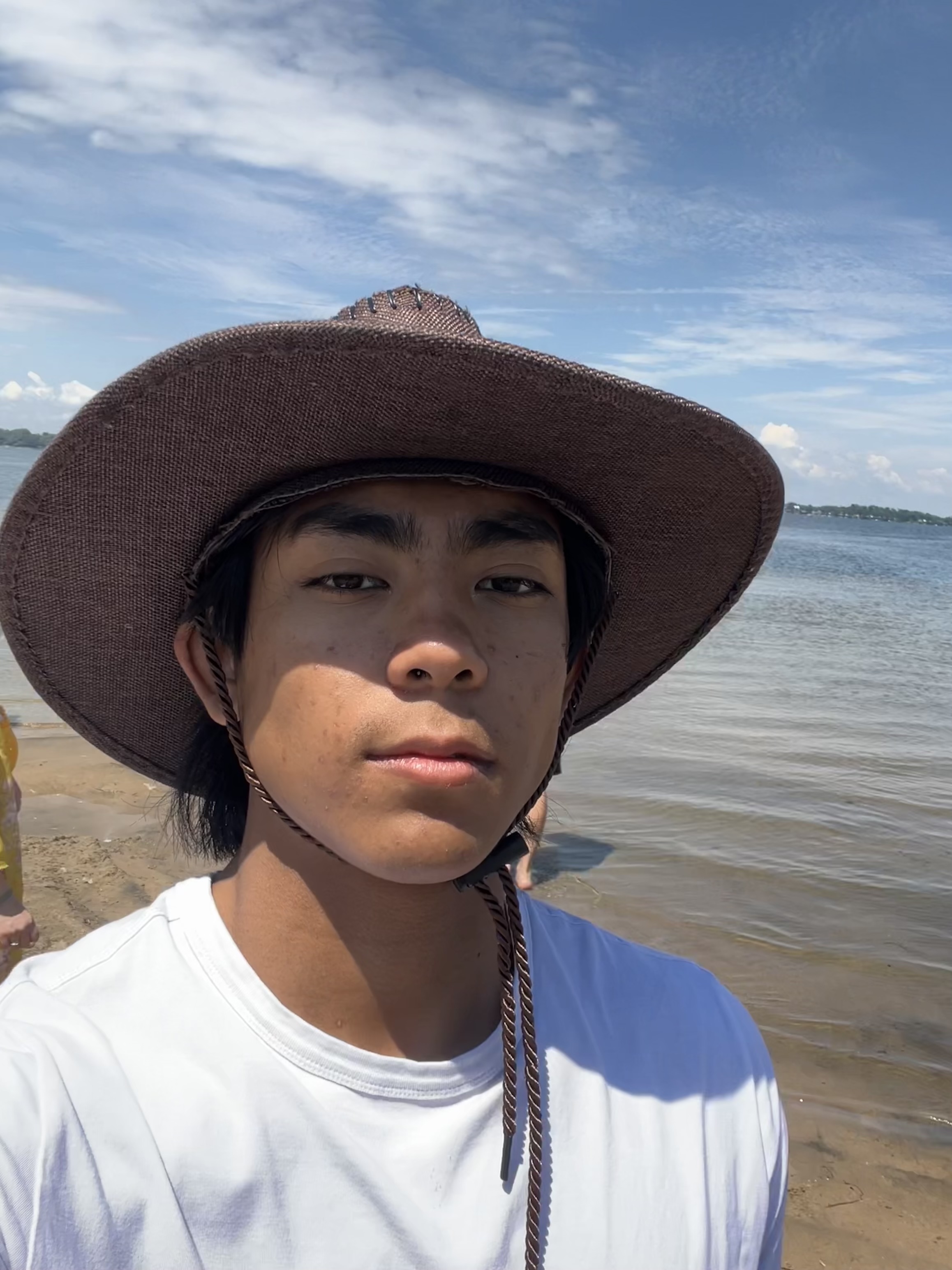 Daniel in a wide-brim hat by the water.